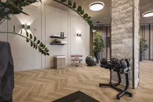 Fitnessraum mit Gewichten, einem Fitnessball, Pflanzen und modernem Design. Holzfußboden und helle Wände schaffen eine einladende Atmosphäre.