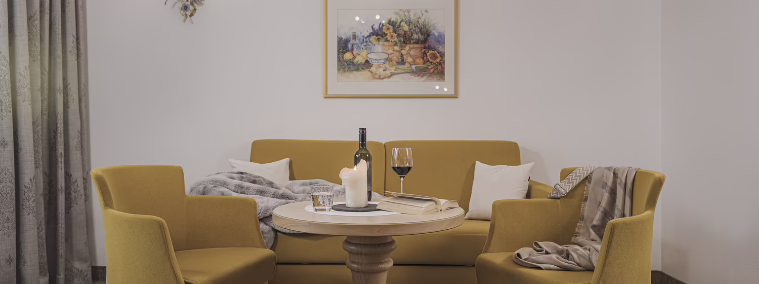 Gemütlicher Wohnbereich der Wohlfühlsuite Rosalie Behagliche Sitzecke der Wohlfühlsuite Rosalie im Hotel Platzlhof mit Sofa, Sesseln und kleinem Tisch.