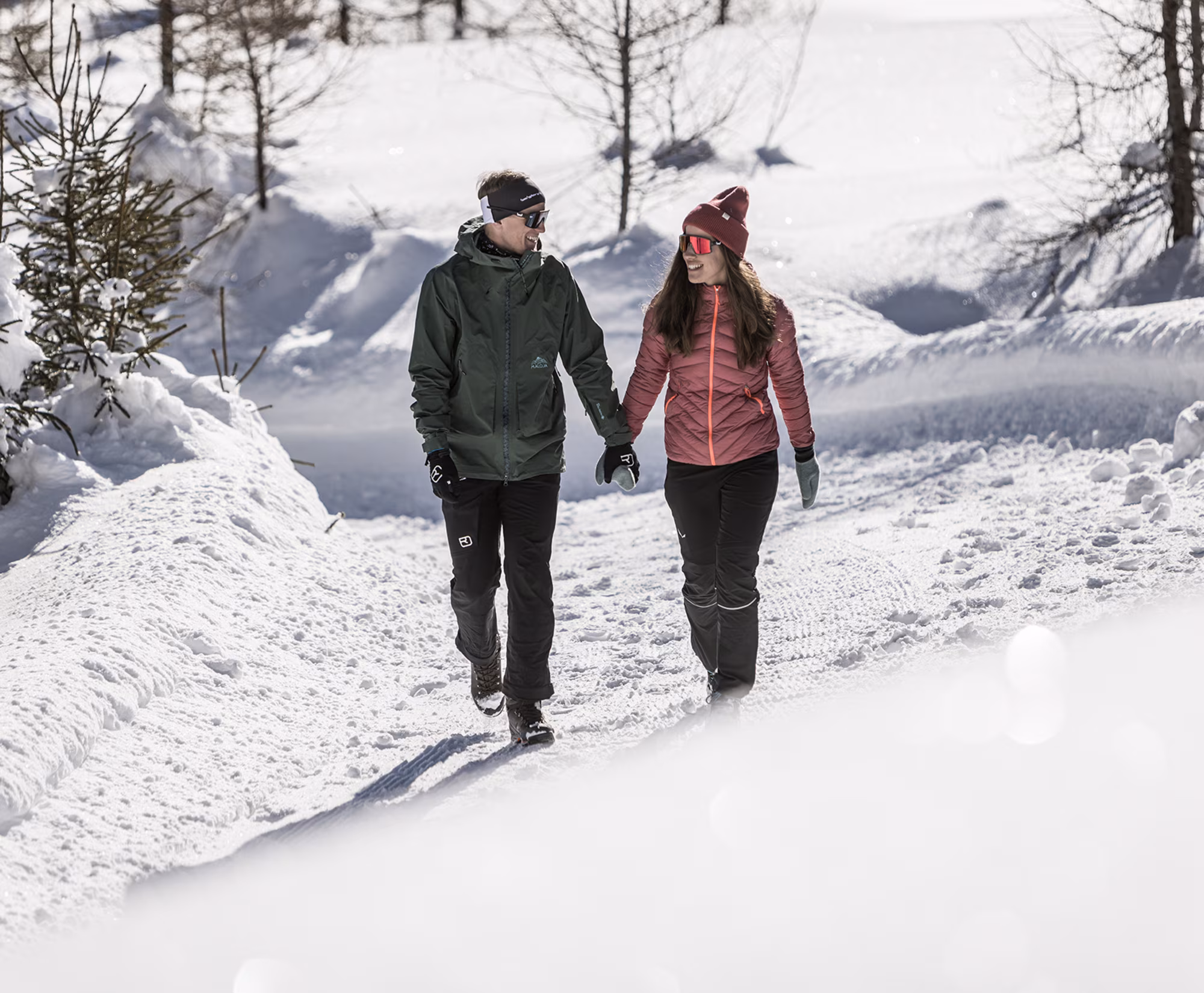 Paar spaziert Hand in Hand auf einem verschneiten Weg.