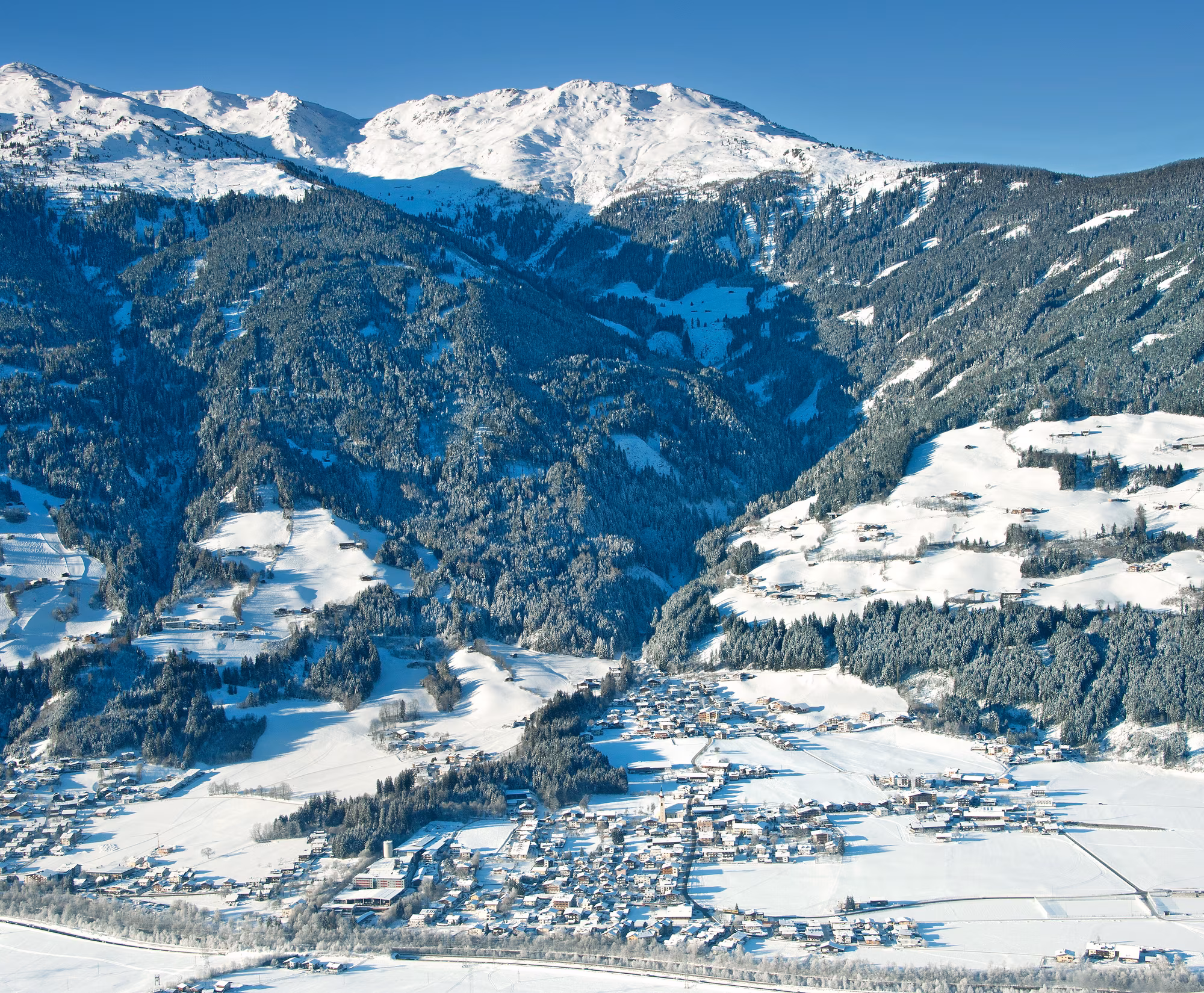 Schneebedeckte Berge und ein Winterdorf in einem Tal.