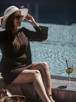 Gast genießt entspannt die Sonne am Pool des Hotel Platzlhof mit Sommerhut und einem erfrischenden Getränk.