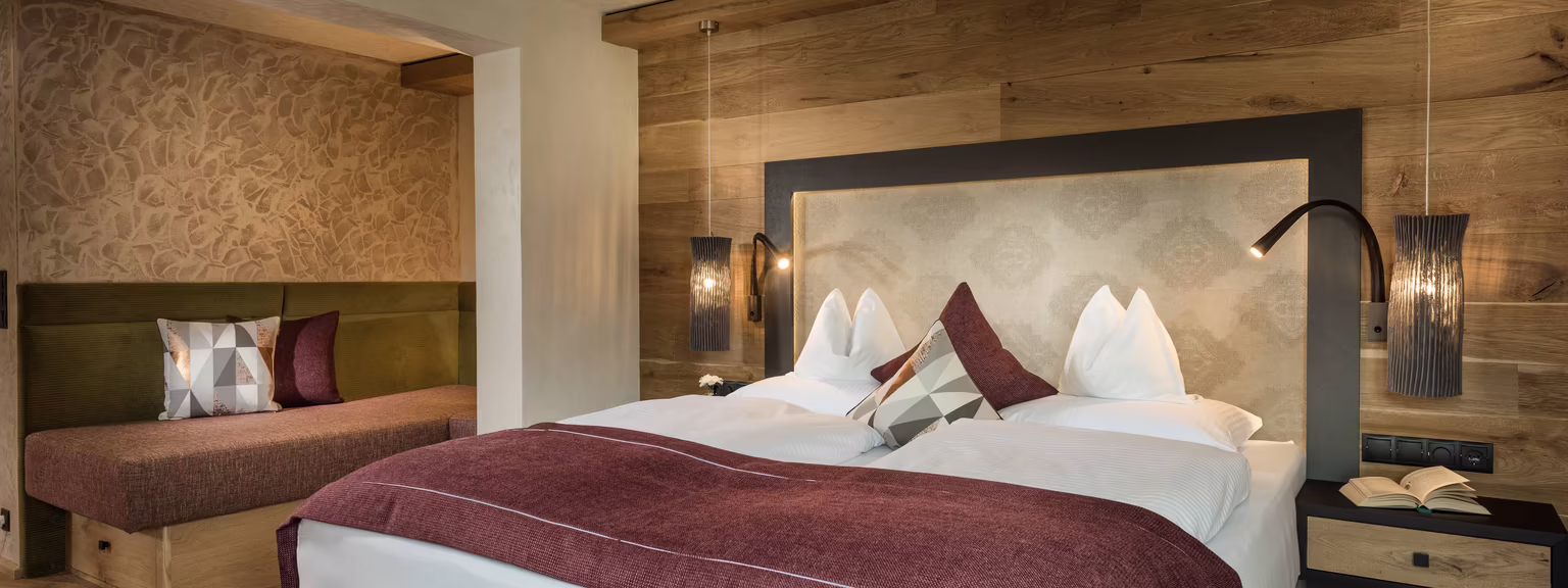 Ruhiger Schlafbereich mit alpinem Charakter Modernes Schlafzimmer mit Doppelbett, einer Schlafcouch und Holzverkleidung, gemütlich mit Kissen und stilvollen Lampen.