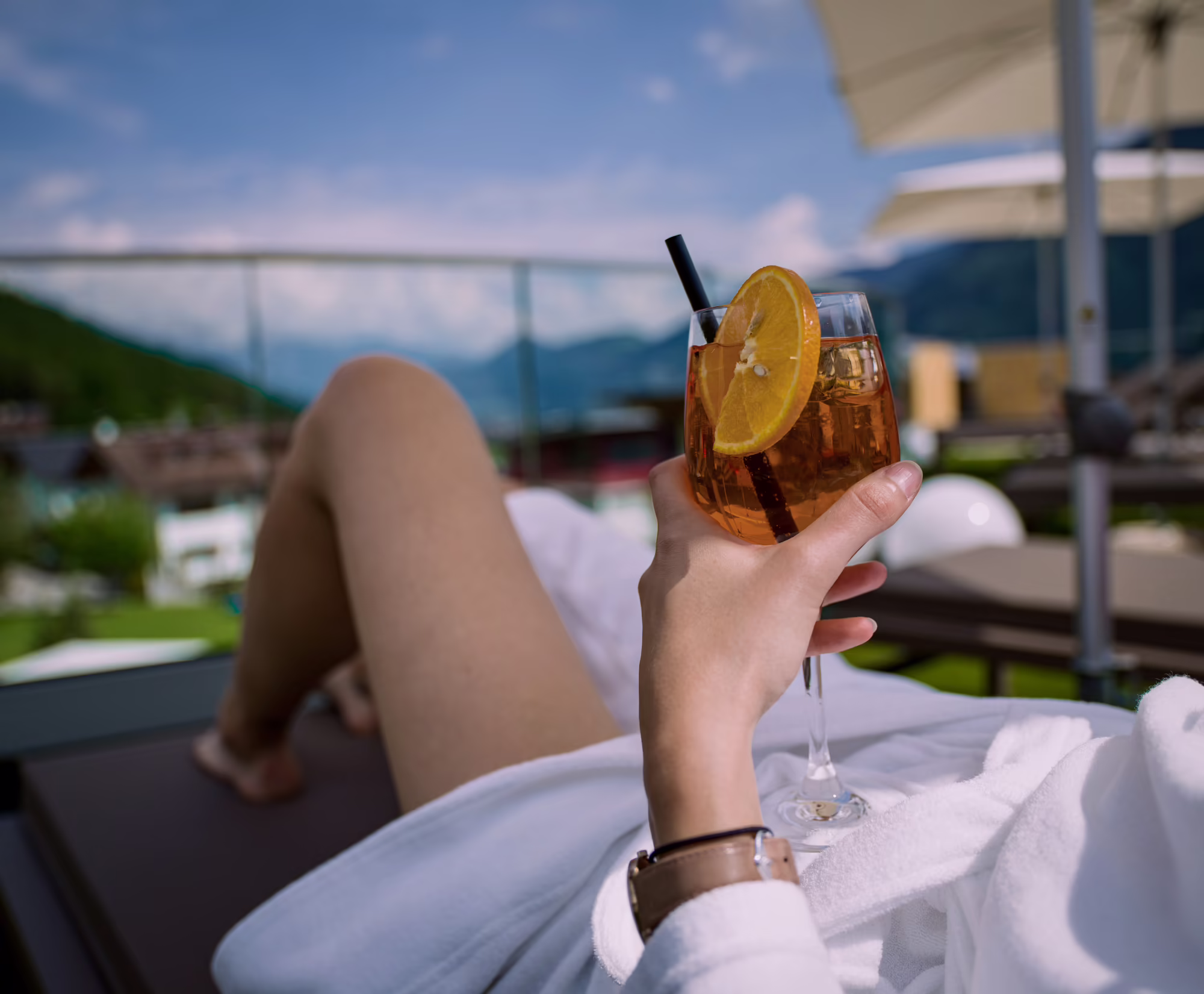 Ein Kaltgetränk auf der Terrasse genießen Frau genießt einen Aperitif auf der Sonnenterrasse vom Hotel Platzlhof