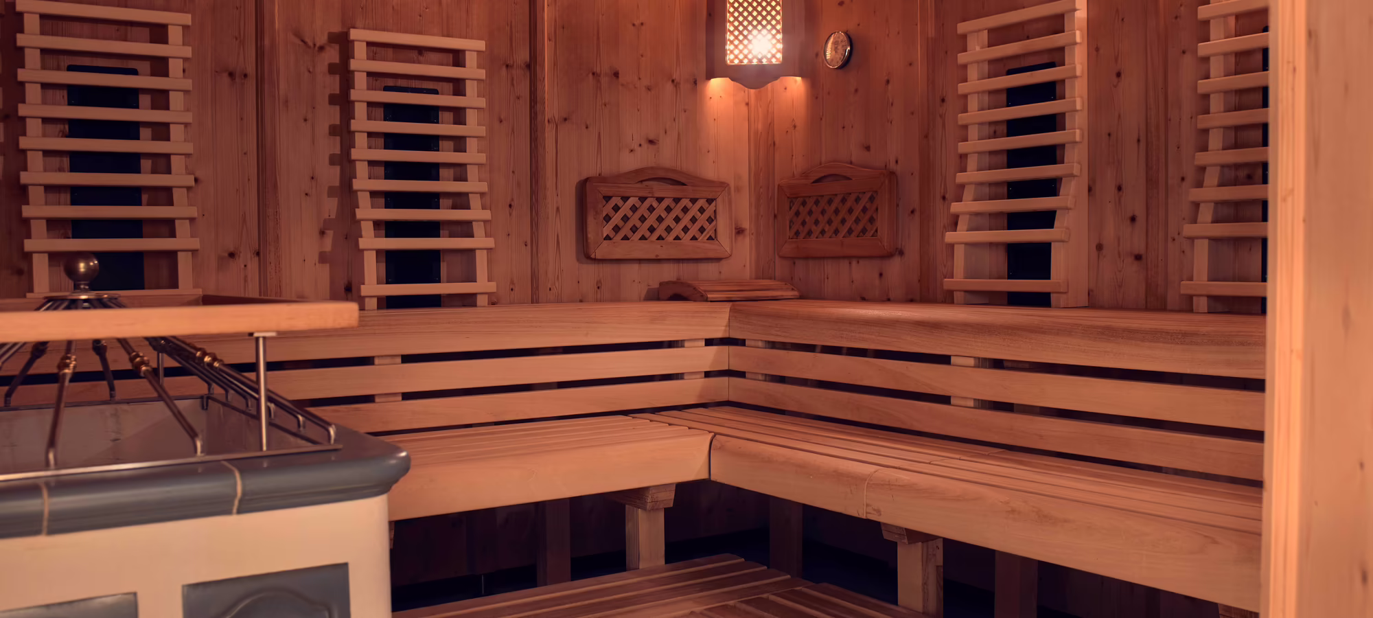 Sauna im Hotel Platzlhof Innenansicht einer Holzsauna mit Bänken und sanfter Beleuchtung. Die Wände sind mit Holz verkleidet und es gibt eine Feuerstelle.