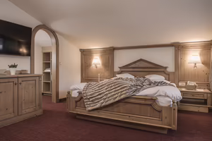 Ein gemütliches Schlafzimmer mit einem Holzbett, dekorativen Wänden und einem Fernseher an der Wand.