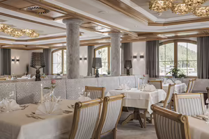 Elegantes Restaurant mit dekorierten Tischen, Stühlen und einem stilvollen Ambiente, beleuchtet von Kronleuchtern und Lampen.