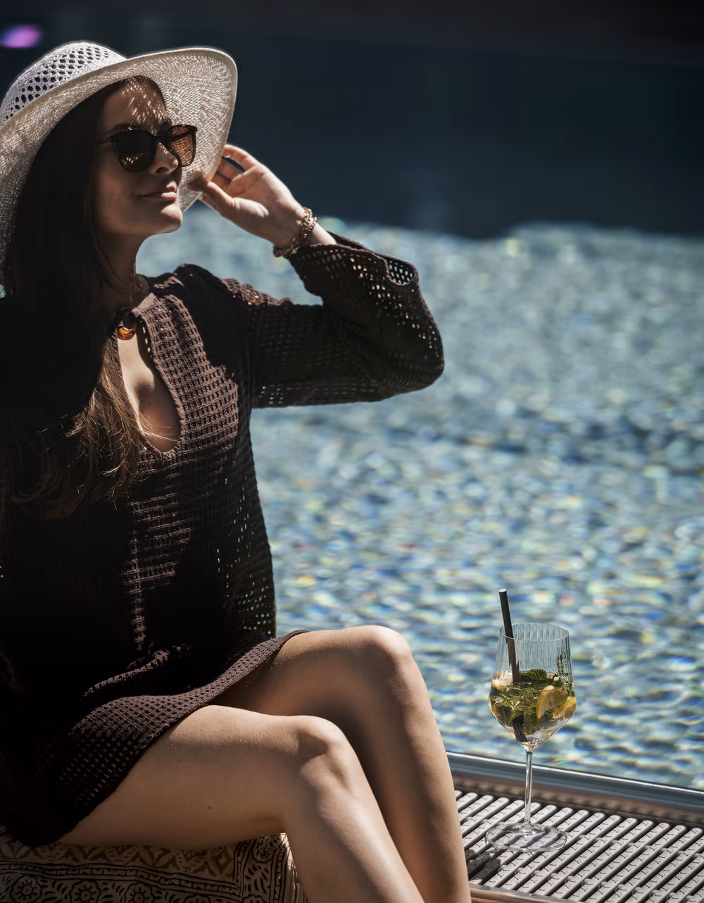 Entspannter Urlaubsmoment am Pool des Hotel Platzlhof mit Sonnenhut, Getränk und sommerlicher Atmosphäre.