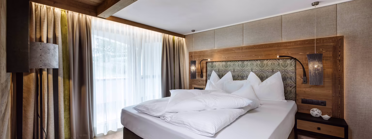 Gemütliches Doppelbett in Sarah’s Jagasuite Großzügiges Doppelbett in Sarah’s Jagasuite mit warmen Holzelementen und behaglicher Atmosphäre im Hotel Platzlhof.