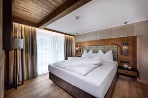 Großzügiges Doppelbett in Sarah’s Jagasuite mit warmen Holzelementen und behaglicher Atmosphäre im Hotel Platzlhof.