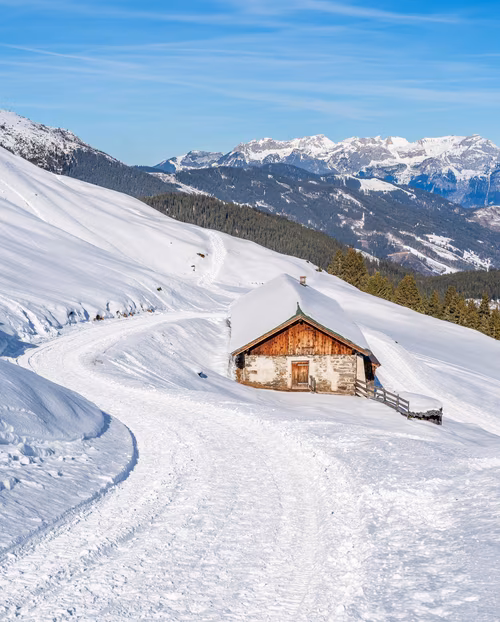 Schneebedeckte Landschaft mit einer Almhütte Haus und präpariertem Winterwanderweg
