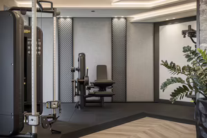 Moderner Fitnessraum mit Trainingsgeräten, einer Hantelbank und dekorativer Wandgestaltung. Grünes Blattwerk ergänzt die Atmosphäre.