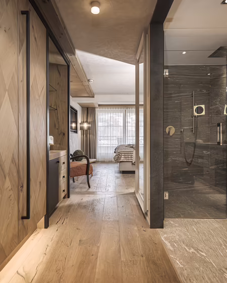 Ein moderner Flur mit Holzfußboden, großen Fenstern und einer gläsernen Dusche im Badezimmer