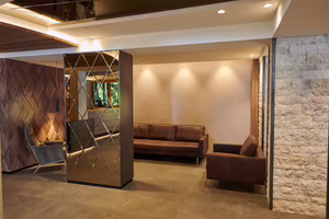 Moderne Lounge mit eleganten Sofas, einem Spiegel und sanfter Beleuchtung, kombiniert mit naturbelassenen Stein- und Holzoberflächen.