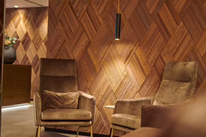 Zwei bequeme Sessel stehen vor einer eleganten Holzvertäfelung mit einem warmen Lichtakzent.