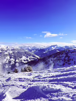 Berglandschaft im Schnee mit schneebedeckten Gipfeln und blauem Himmel.