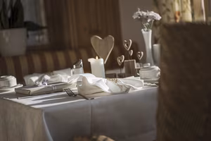 Ein elegant gedeckter Tisch mit Servietten, Besteck, Kerzen und dekorativen Elementen in einem gemütlichen Raum.