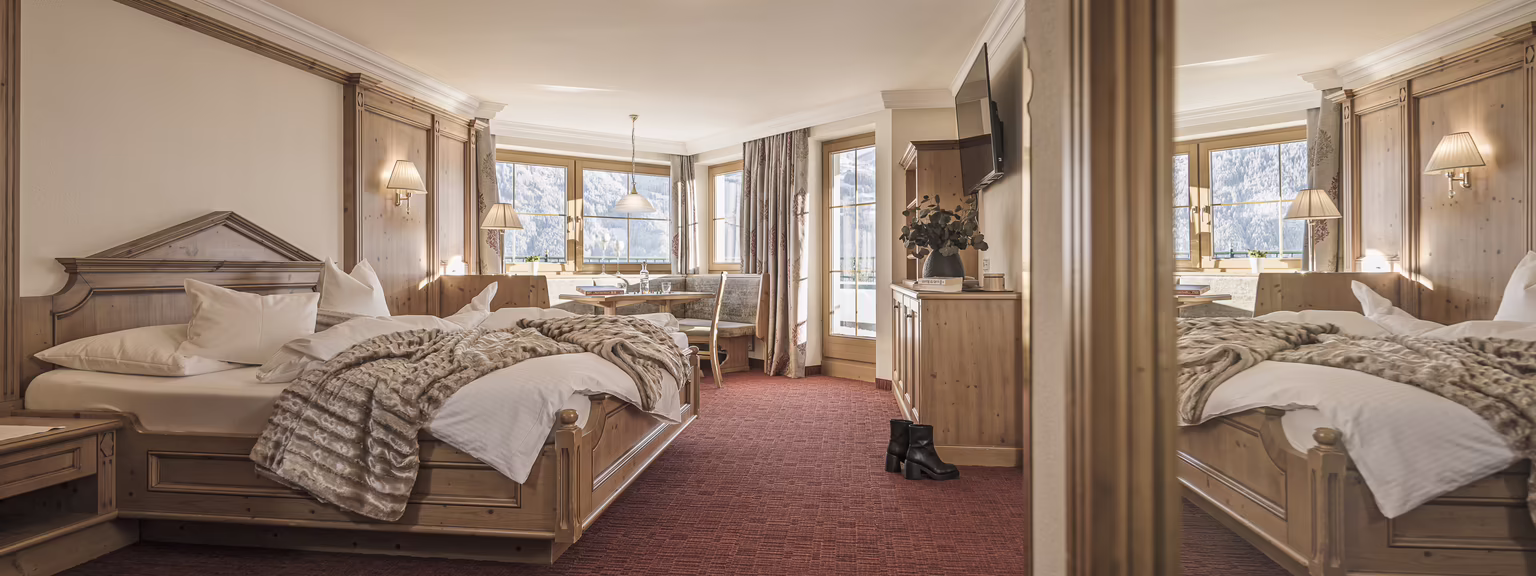 Helles Hotelzimmer mit einem Doppelbett, Tisch und Stühlen, großen Fenstern und gemütlicher Einrichtung.