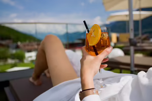 Gast entspannt mit einem Aperitif in der Hand auf der sonnigen Terrasse des Hotel Platzlhof im Zillertal.