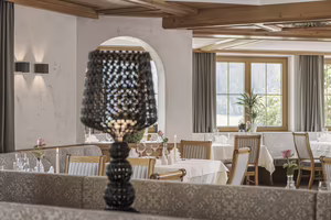 Ein elegantes Restaurant mit Tischen, weißen Tischdecken und dekorativen Elementen, im Vordergrund eine stilvolle Lampe.