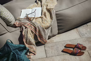 Buch, Sonnenbrille und Sandalen auf einer gemütlichen Liege am Pool des Hotel Platzlhof im Zillertal.