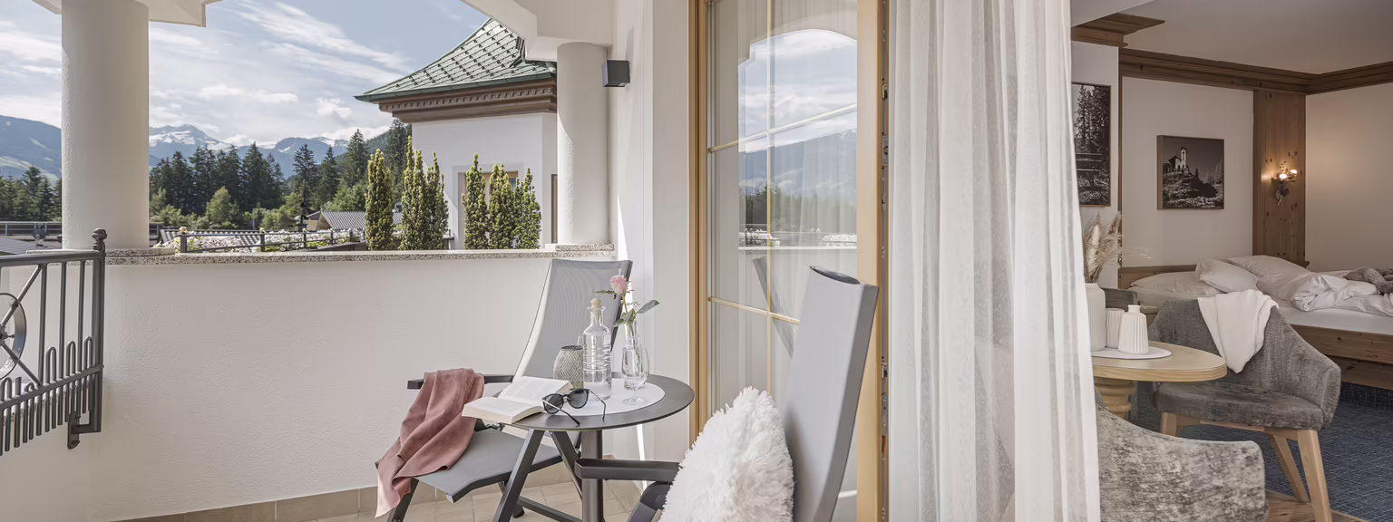 Großer Balkon mit Aussicht im dritten Stock Balkon mit Stühlen und Tisch, Blick auf Berge und grüne Landschaft.