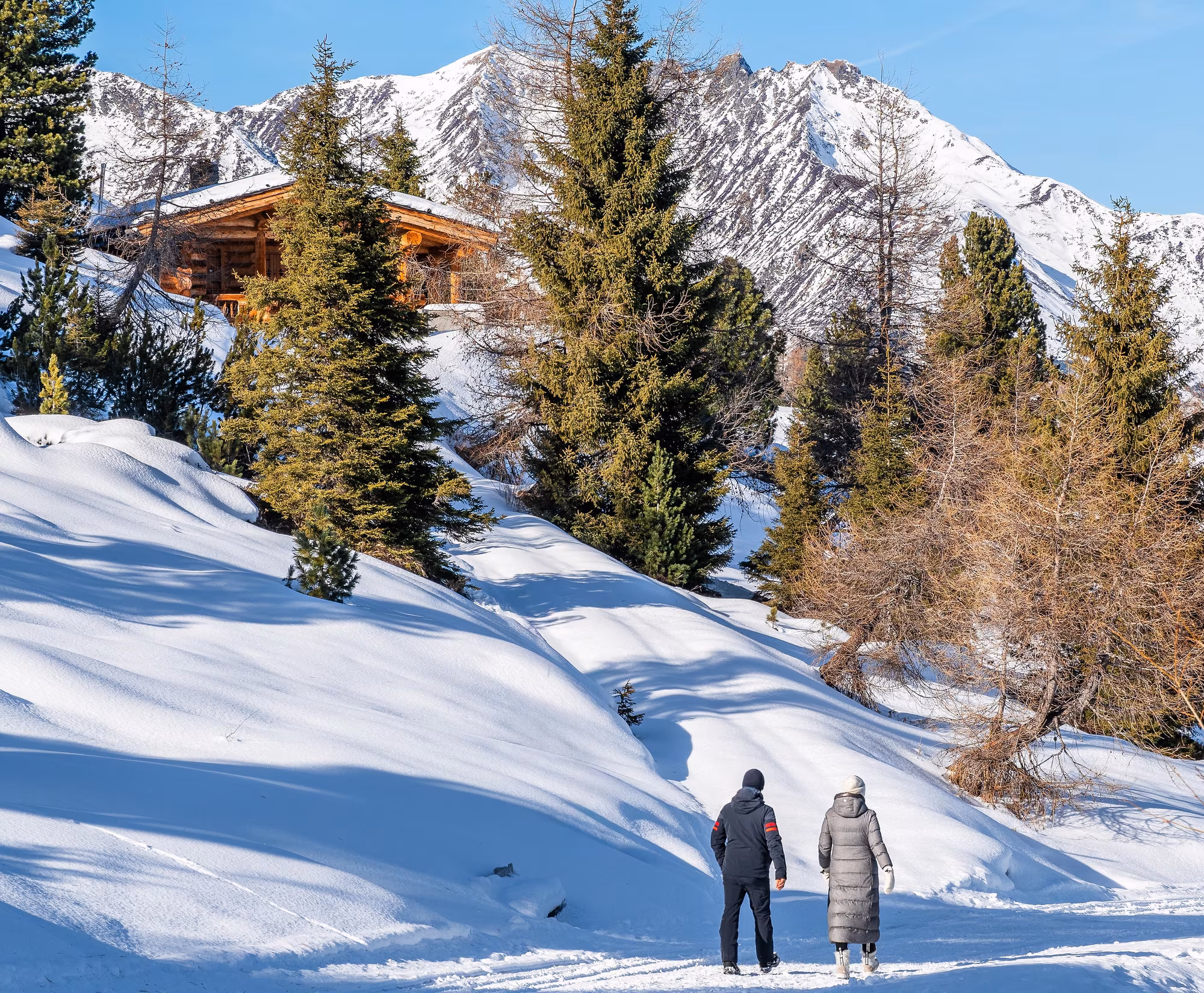 Winterwanderweg bei strahlendem Sonnenschein ©Erste Ferienregion im Zillertal, Franz Kupfner Zwei Personen gehen auf einem verschneiten Winterwanderweg in Hochzillertal in Kaltenbach.