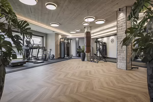 Moderner Fitnessraum im Hotel Platzlhof mit Ausdauergeräten, Kraftstationen und Boxsack für das Training im Urlaub.