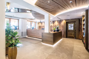 Rezeption im Hotel Platzlhof in Ried im Zillertal mit Altholzdecke, Holzwand im Fischgrätmuster und hellem Steinboden
