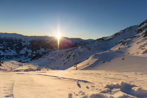 Sonnenaufgang über schneebedeckten Bergen und eine Umgebung, die von frischem Schnee bedeckt ist.